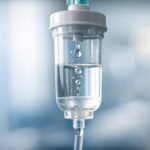 Close-up de câmara de gotejamento de soro hospitalar para cálculo de infusão.